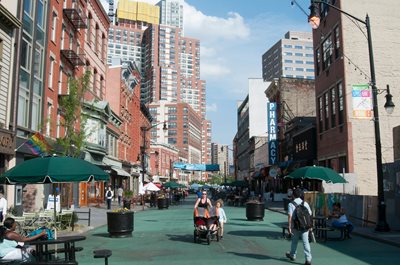 Woman pushes stroller with child walking next to her on Newark Avenue pedestrian plaza Jersey City, New Jersey